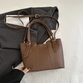 Brown leather bucket bag with top handle and adjustable shoulder strap on neutral background - Brown
