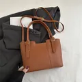 Brown lychee leather bucket bag with dual handles and gold hardware in a chic setup - Brown