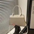 Minimalist beige woven tote bag with smooth leather handles and gold fashion lettering - White