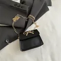 Elegante borsa a sella mini nera con fiocco dorato e tracolla a catena sottile - Nero