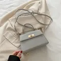 Elegante borsa a mano grigio argento con trama intrecciata e chiusura dorata - Argento