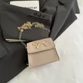 Elegante borsa a sella beige con fiocco, catena dorata e chiusura a patta - Cachi