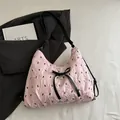 Pink pleated shoulder bag with black bows and heart pendant on a stylish layout - Pink
