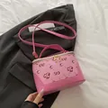 Borsa a tracolla rosa con stampa ciliegie e cerniere dorate su un blazer nero - Rosa