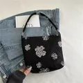 Chique zwarte canvas draagtas met witte bloemenpatronen op een spijkerjasje achtergrond - Zwart