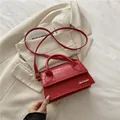 Sac carré rouge élégant avec motif crocodile et logo doré sur blazer beige - Rouge