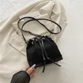 Bolso cubo de ante negro de moda con herrajes dorados y cordón sobre una chaqueta blanca - Negro