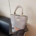 Silver grey nylon handbag with Fashion label on urban minimalist book background - Gray