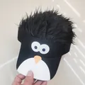 Close-up of funny penguin cartoon embroidery and black synthetic wig on baseball cap - Penguin Cartoon Style / Black & White