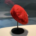 Leuchtend rote Baskenmütze aus Wolltweed mit dezenten Pailletten auf einem Ständer - M / Rot