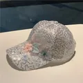 Detail of silver sequined baseball cap with floral accents and faux pearl embellishments - White Butterfly Flower
