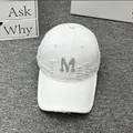 Detailed close-up of a white distressed baseball cap featuring a silver glitter M patch - Adult One Size (Adjustable) / White