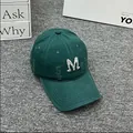 Detail view of distressed dark green baseball cap with rhinestone M letter and frayed edges - Adult One Size (Adjustable) / Green