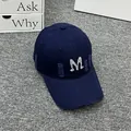 Close-up of distressed denim baseball cap with white embroidered M and ripped detail - Adult One Size (Adjustable) / Navy Blue