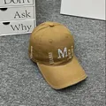 Close-up of distressed khaki baseball cap with rhinestone M embroidery and frayed edges - Adult One Size (Adjustable) / Caramel color
