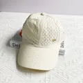 Detail of off-white baseball cap showing laser-cut breathability holes and gold metal logo - Adult One Size (54-59cm) / Beige