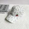 Détail de la casquette en dentelle florale avec breloque cerise sur fond blanc - Adulte, Réglable / Violet