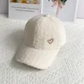 Primer plano de gorra de lana de alpaca blanca con textura suave y detalle de corazón dorado - Blanco
