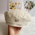 Detalle de boina de lana beige con un emblema de mariposa metálica y tejido suave - M (56-58cm) / Blanco Roto