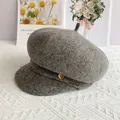 Détail d'une casquette gavroche en laine grise avec emblème en métal doré élégant - L (56-60cm) / Gris