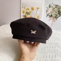 Detalle de boina de lana negra con un adorno metálico de mariposa dorada - M (56-58cm) / Negro