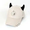 Dettaglio del cappellino beige con corna da diavolo nere e ciondolo smile in metallo - L (56-60cm) / Beige (Anello Sorriso)