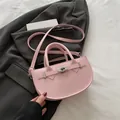 Elegante borsa a sella rosa con chiusura a scatto argento e tracolla su blazer grigio - Rosa
