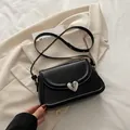 Sac à bandoulière noir minimaliste avec boucle en cœur argenté sur costume beige - Noir