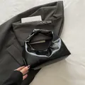 Borsa a gnocchi nera lucida con manico a nodo su elegante sfondo grigio abito - Nero