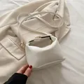 White snake pattern mini pillow bag with gold hardware on a beige blazer - White