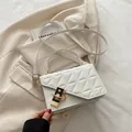 White quilted crossbody bag with gold-tone hardware and adjustable strap on a blazer - White