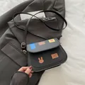 Borsa a sella nera vintage con toppe decorative colorate su un blazer grigio scuro - Nero