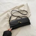 Elegant black faux-leather baguette bag with crocodile pattern and gold twist lock clasp - Black