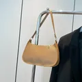Light brown Saffiano leather baguette bag with gold zipper on a minimal hanger - Khaki