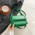 Emerald green PU leather crossbody bag with flap and gold hardware on a gray blazer background - Green