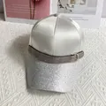 Detailed view of white satin baseball cap with silver glitter brim and rhinestone buckle - White