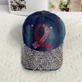 Close-up of pink rhinestone ribbon on navy denim baseball cap with crystal brim detail - Pink Ribbon Style
