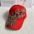 Dettaglio di cappello rosso con ricami floreali dorati e strass luminosi sulla visiera - Rosso