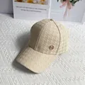 Detailed view of beige houndstooth baseball cap featuring a premium golden metal logo - Khaki
