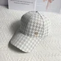 Detail of light grey houndstooth baseball cap with a diamond-studded M-badge logo - White