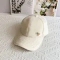 Dettaglio del cappellino in peluche bianco panna con fiocco dorato e perla sintetica - Taglia Adulto (Regolabile) / crema