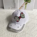 Detailed view of colorful rhinestone bow and silver studs on white denim baseball cap - Bow / White