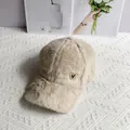 Detail der flauschigen Kunstfell-Baseballkappe mit elegantem goldenen Schmetterlings-Abzeichen - Verstellbar / Beige
