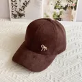 Dettaglio di un cappellino in peluche marrone scuro con fiocco dorato e perla - Taglia Adulto (Regolabile) / caffè