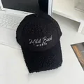 Detailed view of white embroidered lettering on a black fluffy faux shearling baseball cap - Adjustable / Black