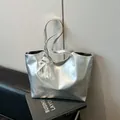 Minimalist silver metallic tote bag with lace pearl bow charm on a leather sofa - Silver with Charm