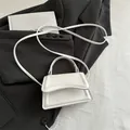 Minibolso bandolera de piel blanca con solapa curva sobre una elegante chaqueta negra - Blanco