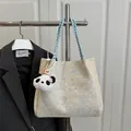 Gestrickte Tragetasche in Beige und Blau mit Panda-Anhänger an einem Kleiderbügel hängend - Blau