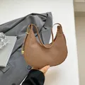 Braune gewebte Hobo-Tasche mit goldenem Metallschloss für Damen in stilvoller Kulisse - Braun