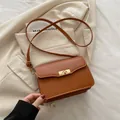 Vintage brown rectangular crossbody bag with a golden metallic twist lock on beige blazer - Brown